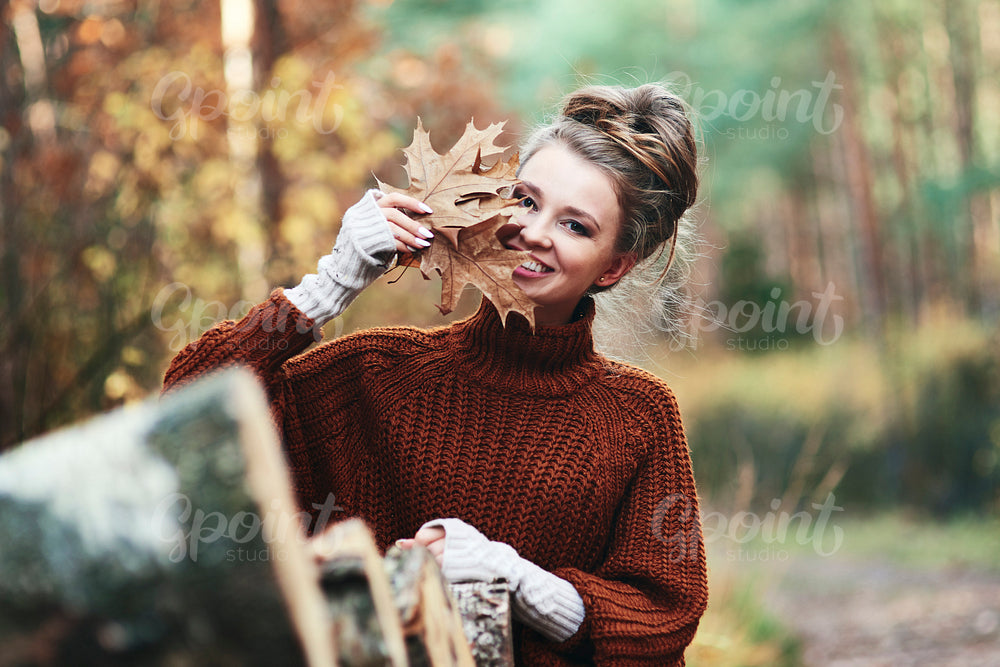 Portrait of young woman with autumnal leaves in forest