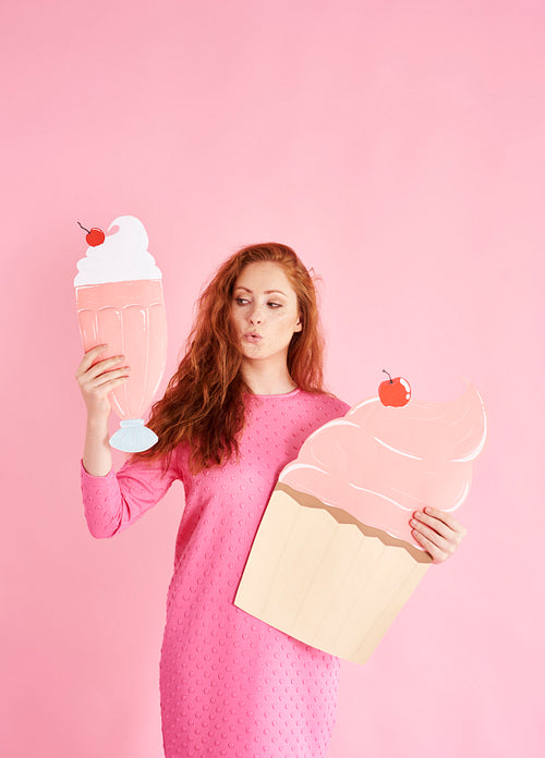 Young woman holding a cupcake and milkshake at studio shot