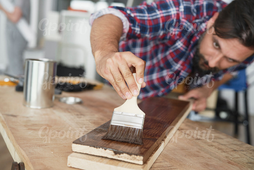 Carpenter painting a raw board with a protective preparation