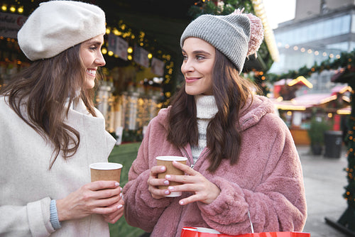 Two friends on a Christmas market drinking mulled wine
