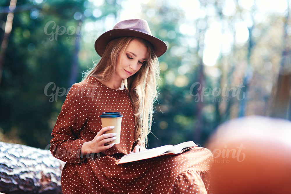 Woman having coffee break in the autumnal forest