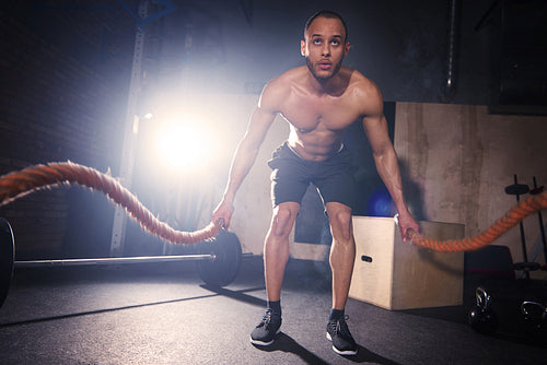 Male athlete working with rope at gym