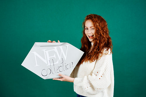 Playful woman holding banner "New collection"
