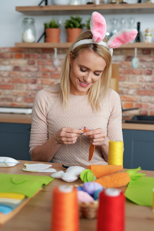 Woman in a rabbit's ears sews Easter decorations