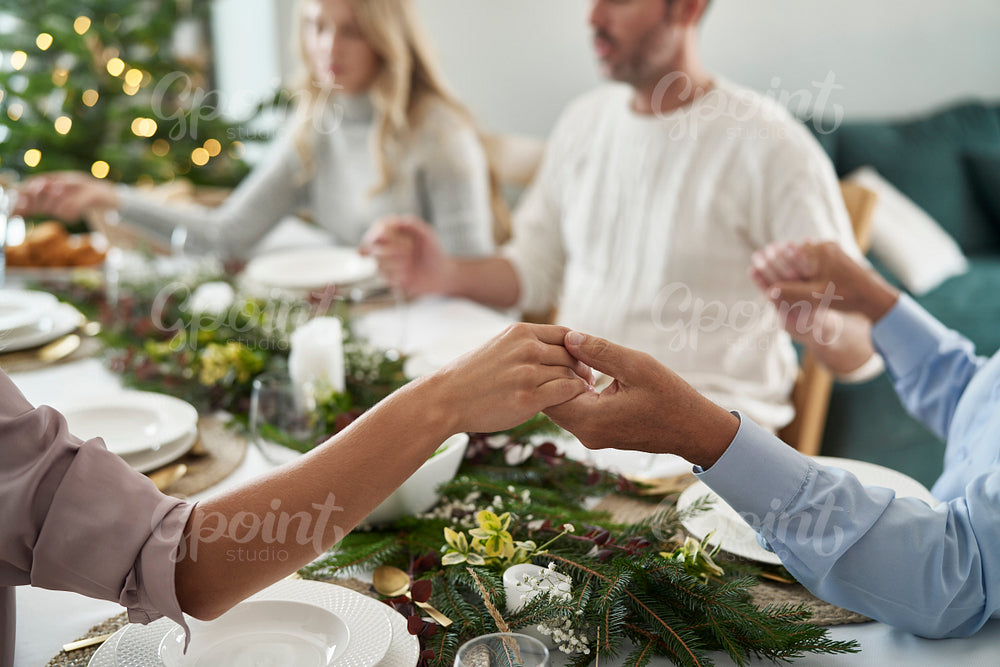 Close up of holding hands of caucasian family sitting around the table and praying 