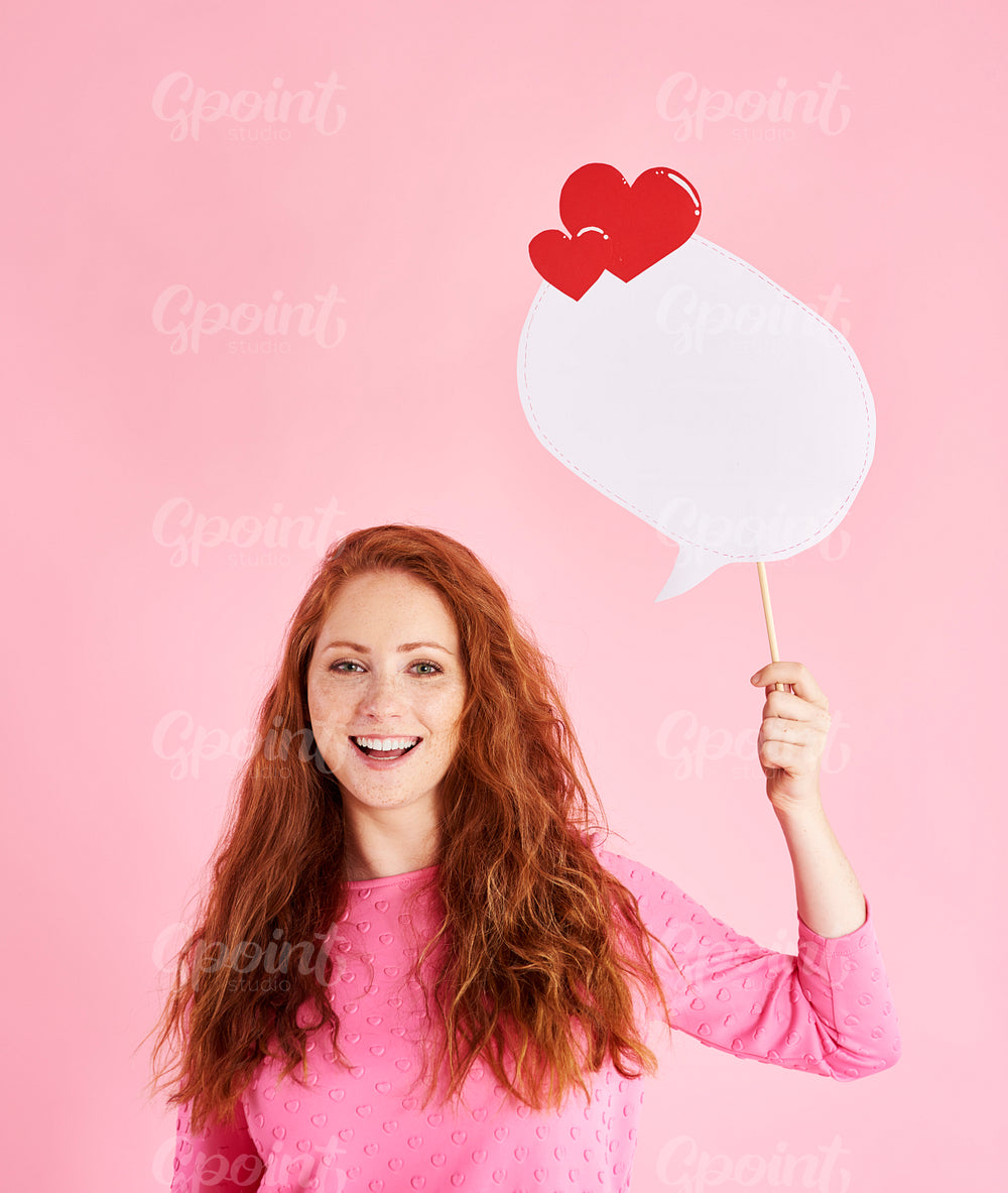 Portrait of cheerful woman holding speech bubble at studio shot