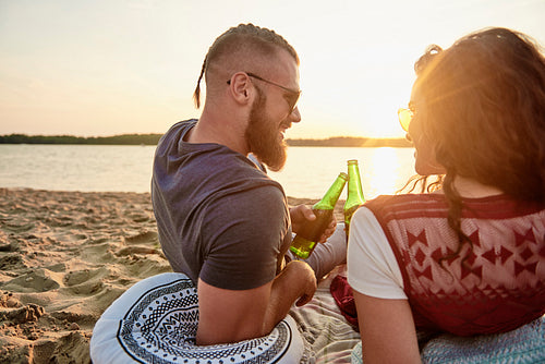 Rear view of young couple drinking beer on the beach