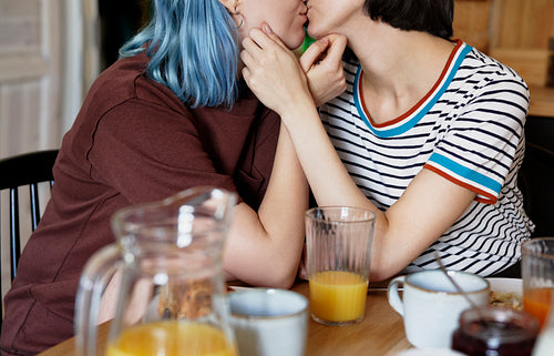Unrecognizable lesbian couple kissing during breakfast