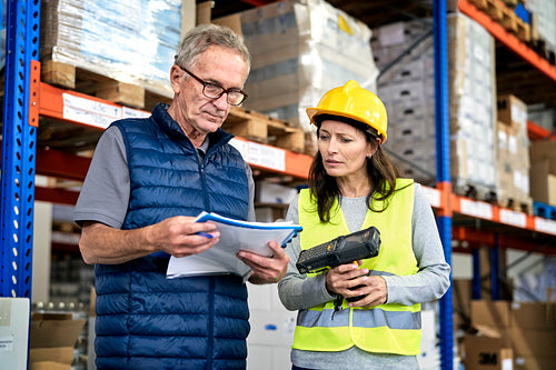 Two caucasian workers in mature age discussing together in warehouse