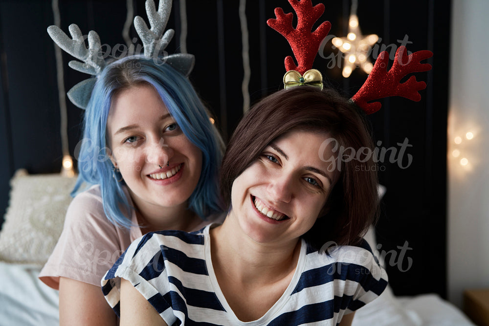 Portrait of happy lesbian couple in Christmas headbands
