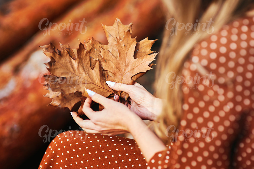 Close up of woman with a bunch of autumnal leaves