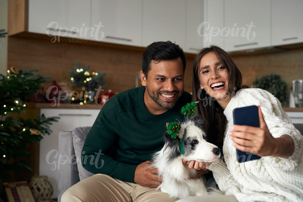 Happy couple make a selfie with dog during the Christmas 