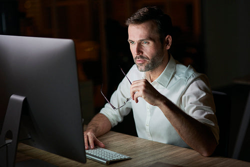 Focused man using computer at night