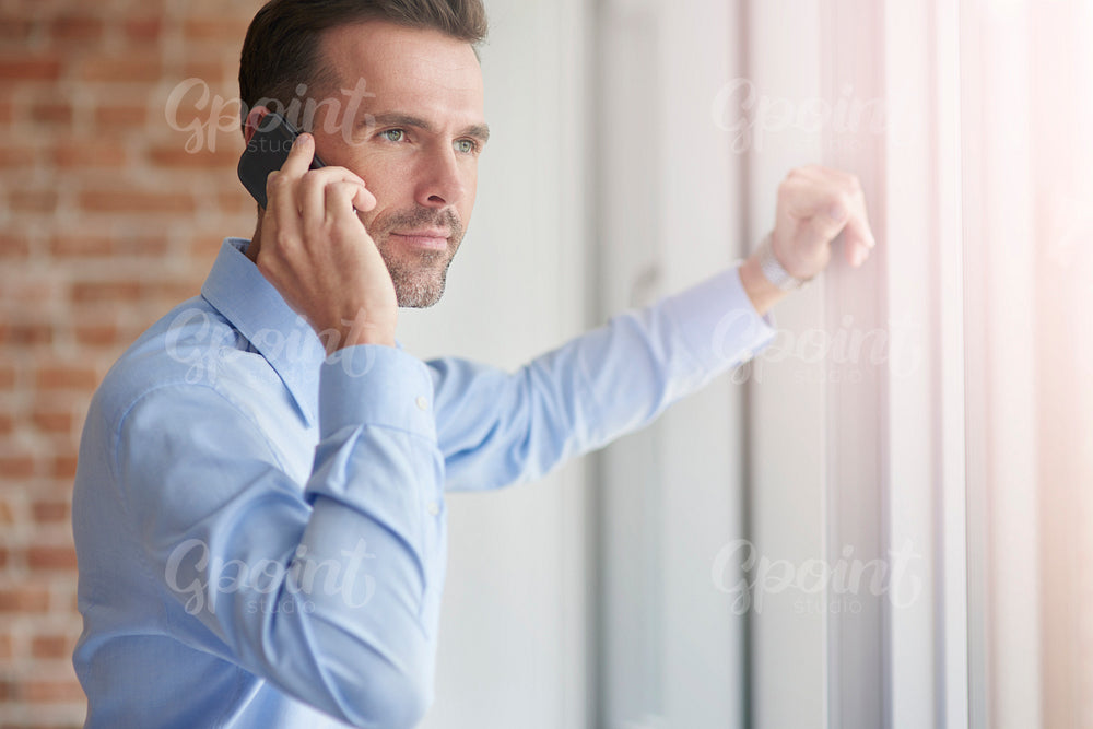 Businessman with phone leaning on the window