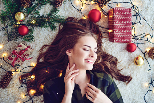 Woman surround by christmas lights lying on floor and dreaming