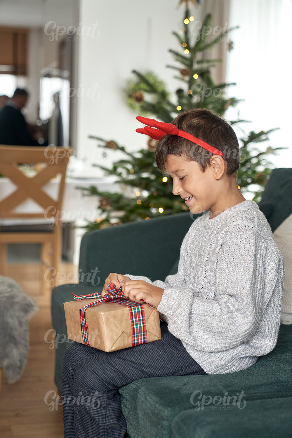 Caucasian boy about to open Christmas gift while sitting on sofa