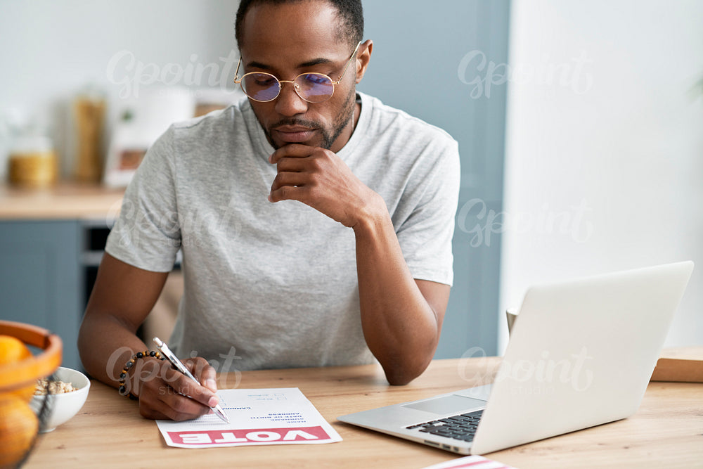 Young black man fulfilling document of mail voting