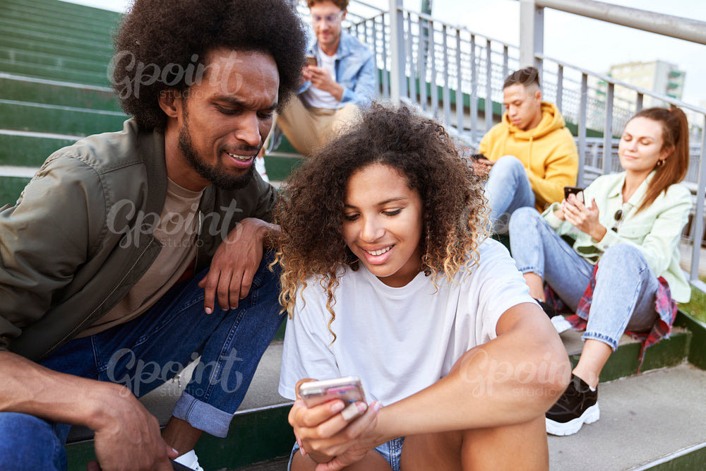 Young people sitting with your mobile phones outdoors