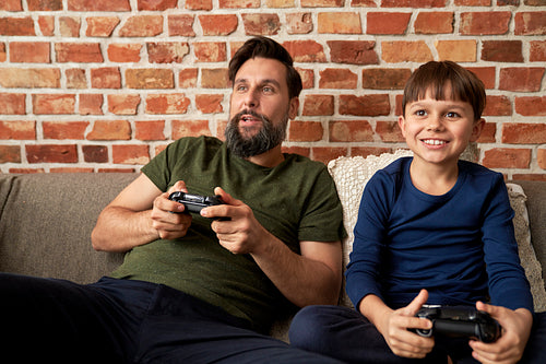 Happy father and son playing video game on couch