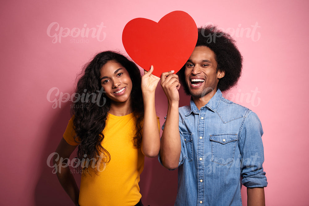 Young African couple holding a red heard in studio shot.