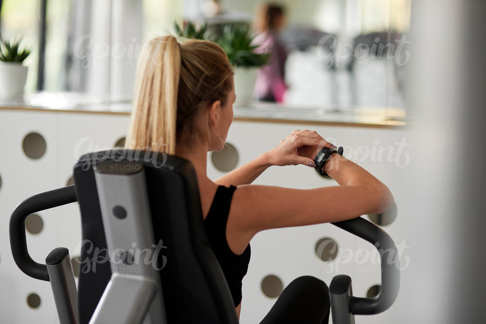 Rear view of female athlete using technology at the gym
