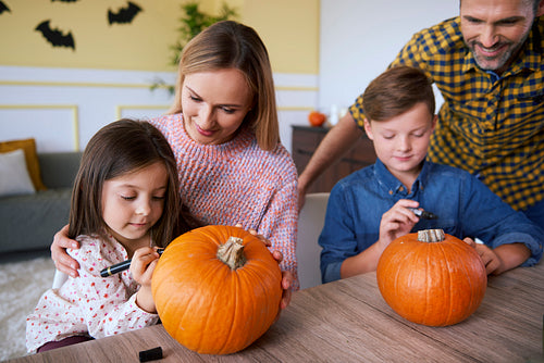 Children and parents drawing on pumpkins
