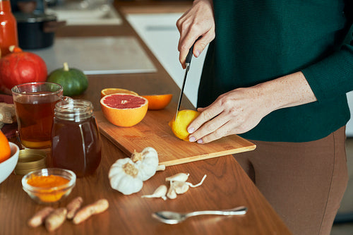 Unrecognizable woman cutting lemon for winter tea