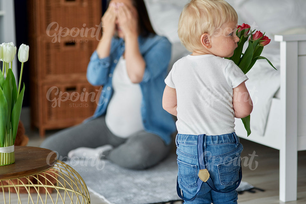 Toddler boy holding flowers for his mother