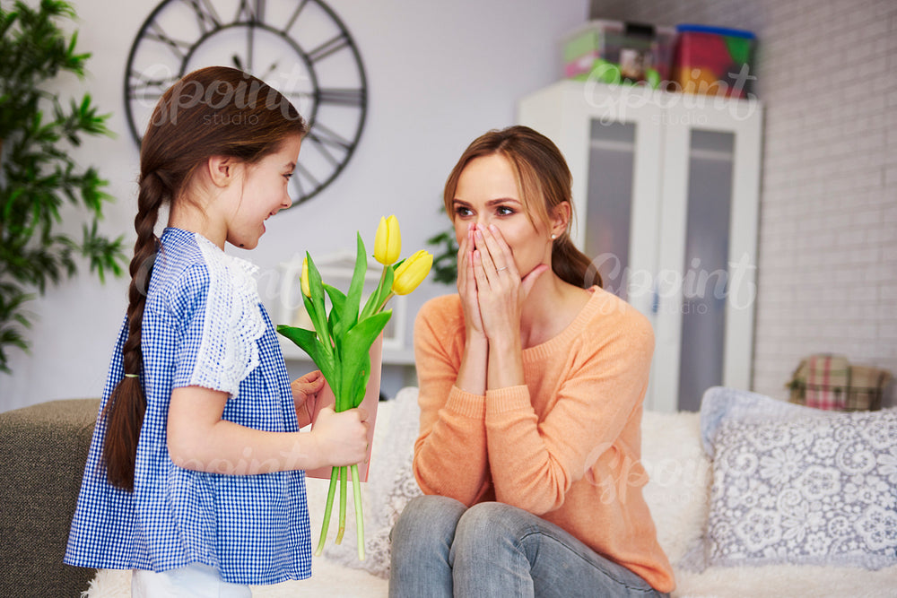 Girl giving her mom the flowers and greeting card