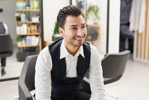 Smiling barber sitting in hair salon