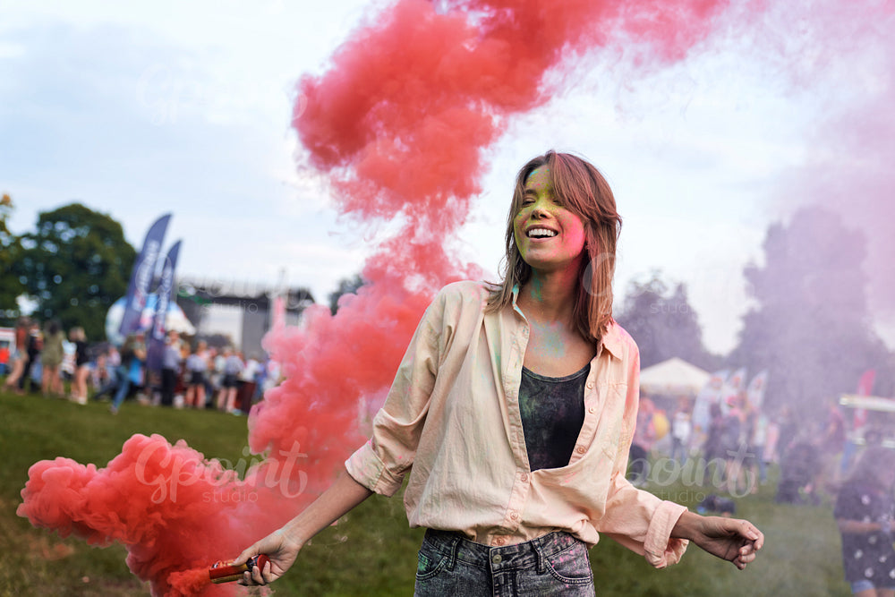 One woman dancing with coloured smoke bombs at Holi Festival