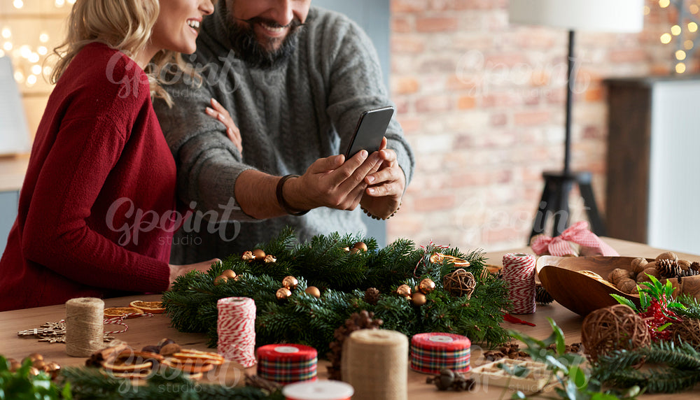 Couple taking photos of the Christmas wreath on the table