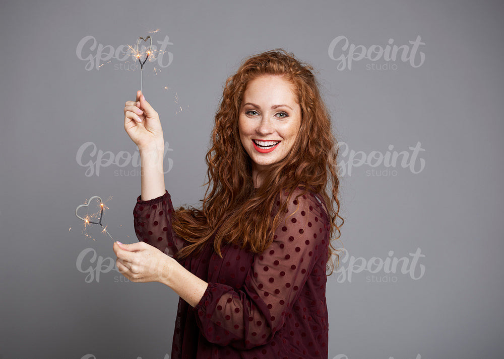 Portrait of happy woman with heart shaped sparklers