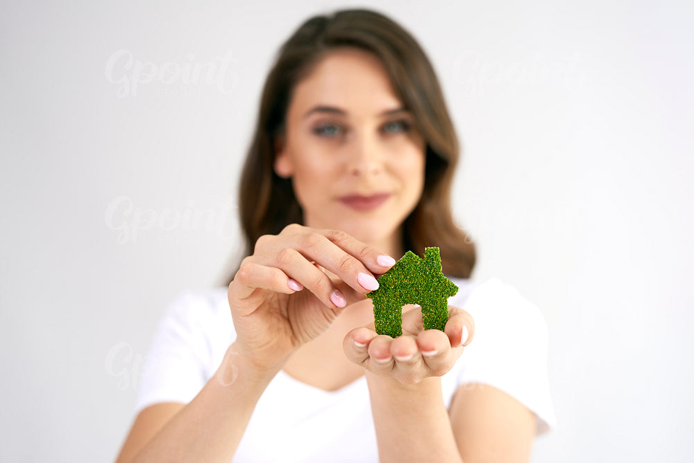 Woman's hand holding eco house icon