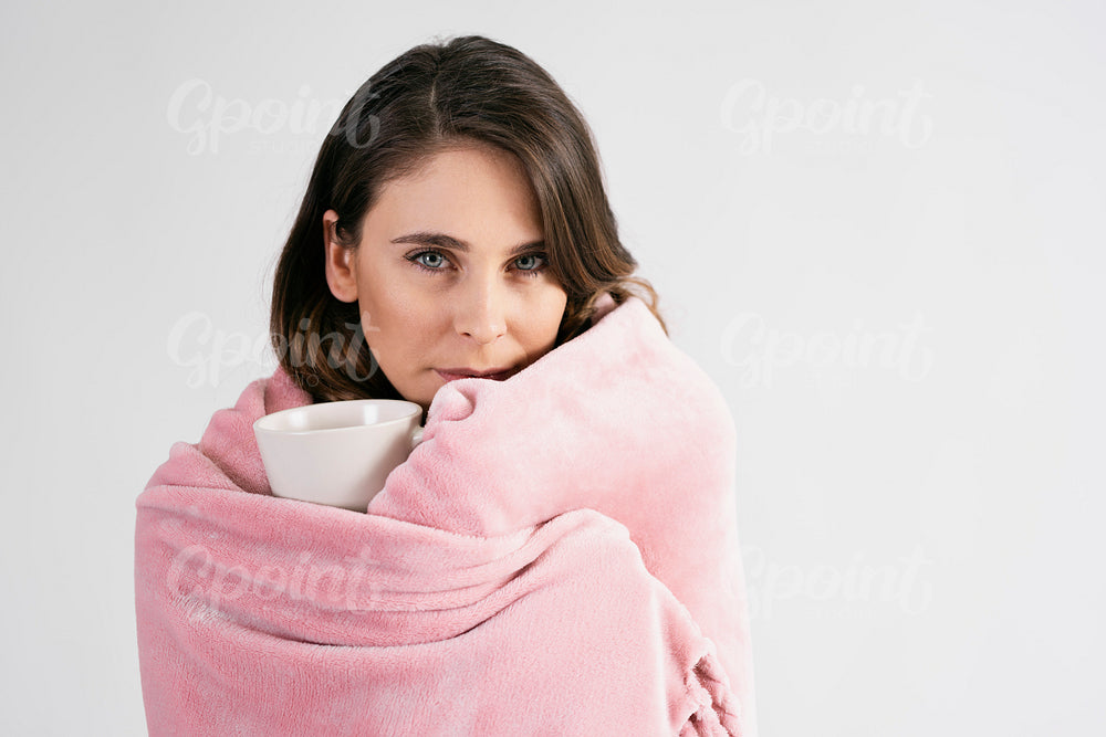 Woman wrapped in blanket holding a mug of hot tea