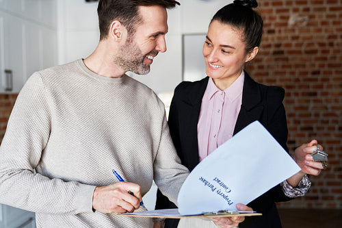 Happy man with estate agent signing contract of new apartment