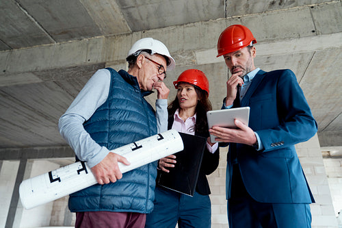 Medium shot of group of caucasian engineers and investors discussing on construction site