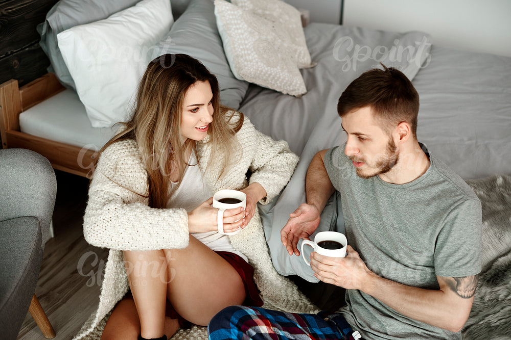 Couple with coffee sitting on floor and talking