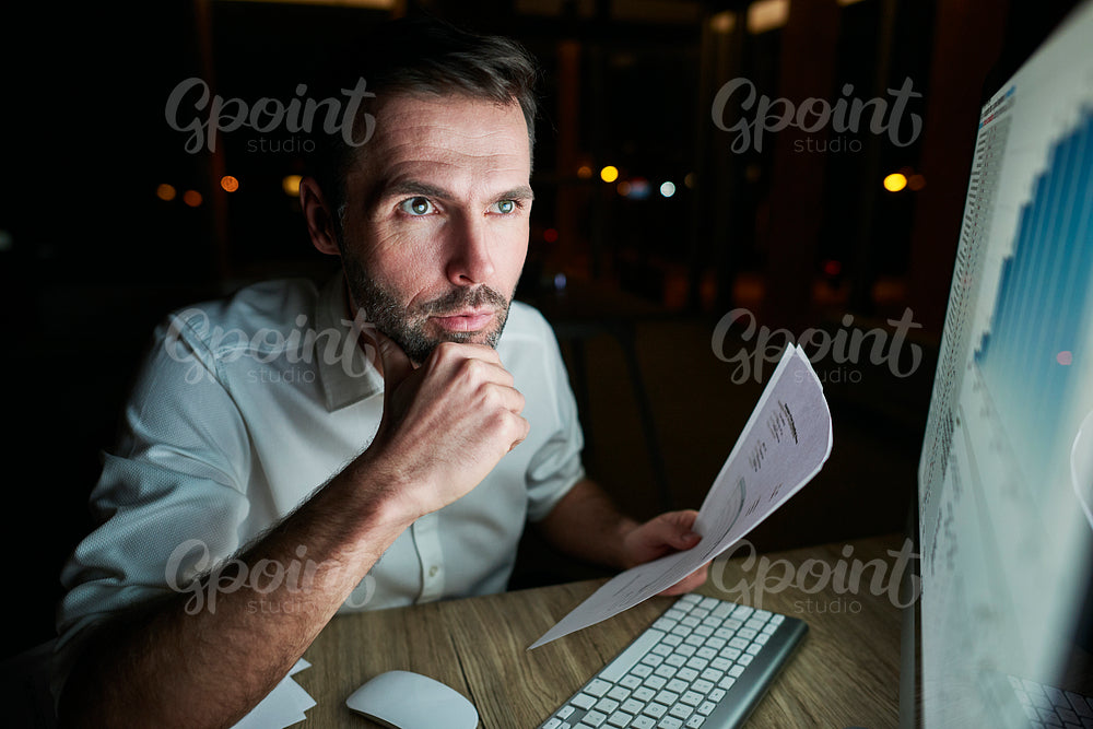 Focused man analyzing document at night