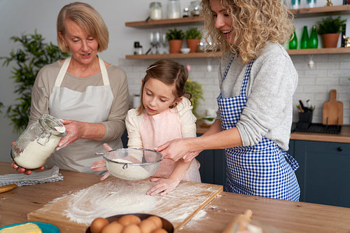 Smiling women sift the flour for Easter baking