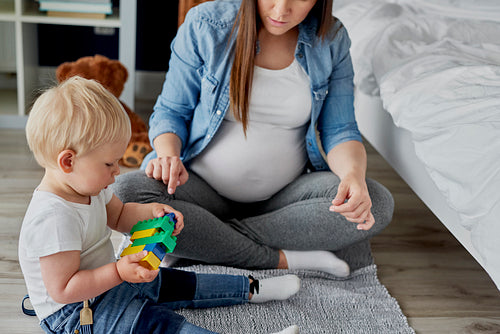 Pregnant mother playing toy blocks with her baby son