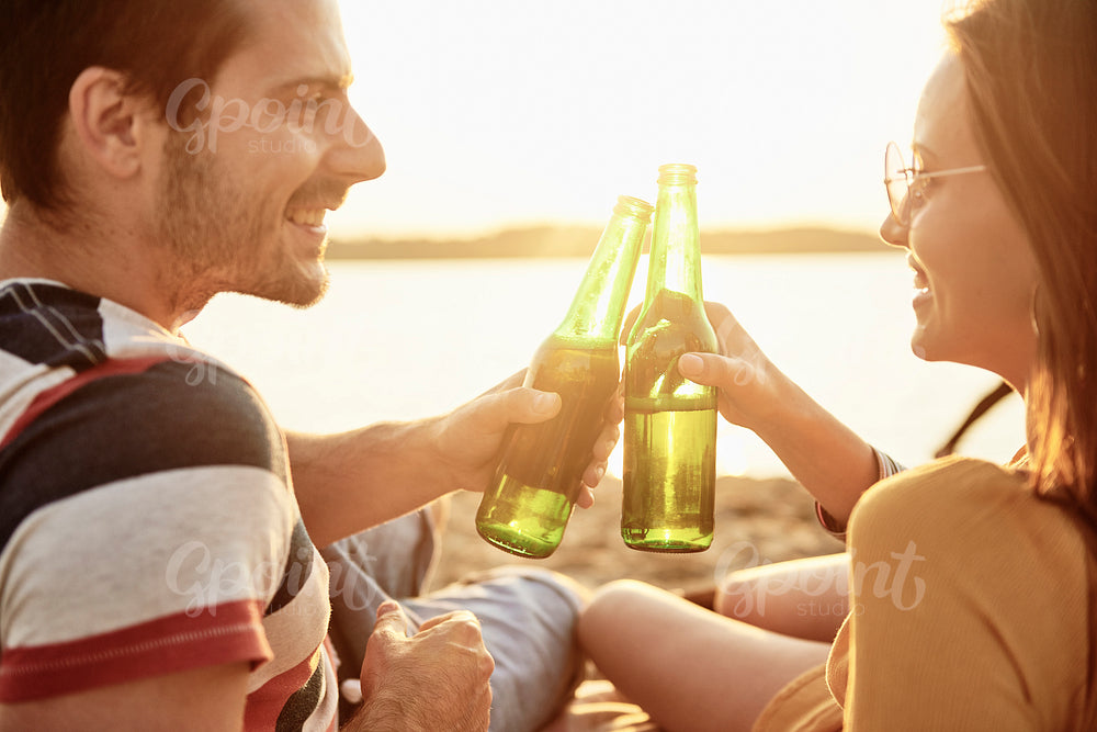 Young couple drinking beer on the beach