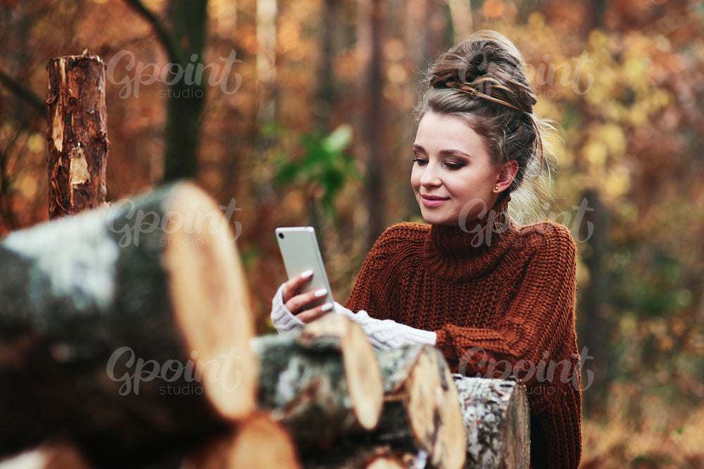Beautiful young woman using phone in forest