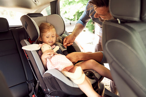 Father fastening seat belt for daughter