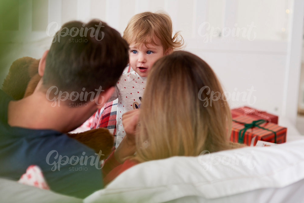 Rear view of baby with parents in bed