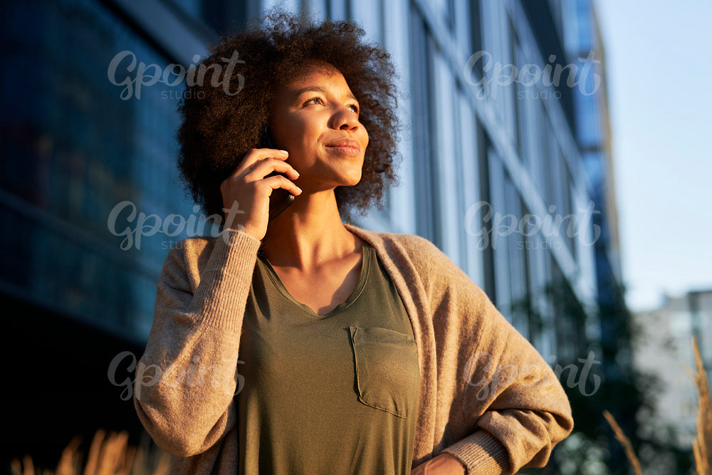Woman with mobile phone in the city during sunset