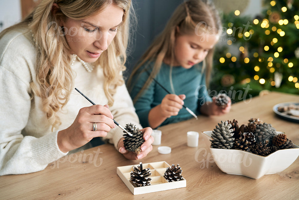 Caucasian woman and daughter decorating cone with white paint