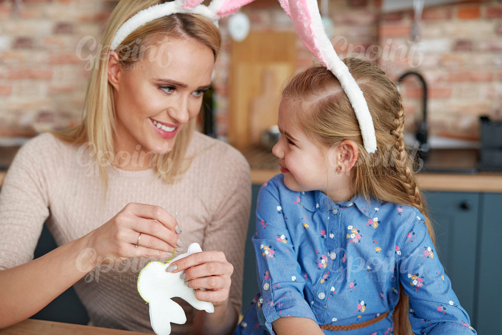 Mother and daughter in rabbit ears sewing Easter bunnies