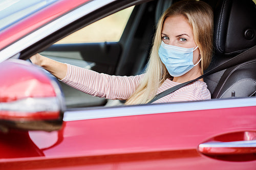 Woman in a protective mask driving a car