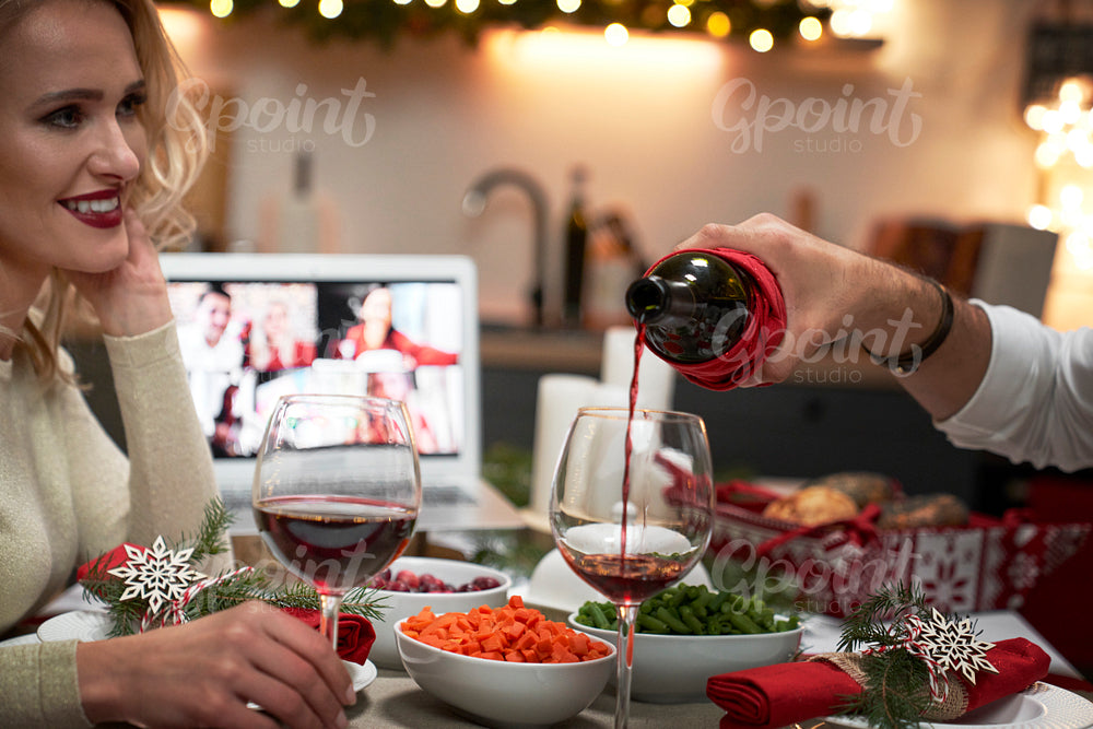 Close up of couple pouring red wine during Christmas dinner